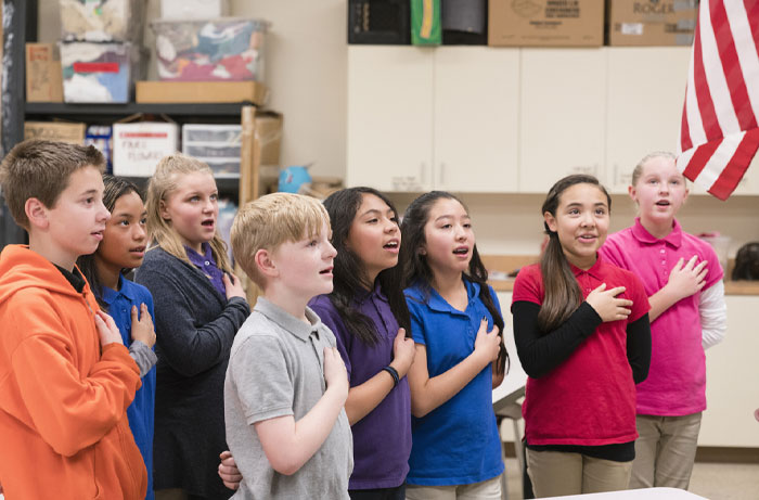 Group of elementary students with hands on hearts reciting the pledge, representing average IQ in the USA education settings.
