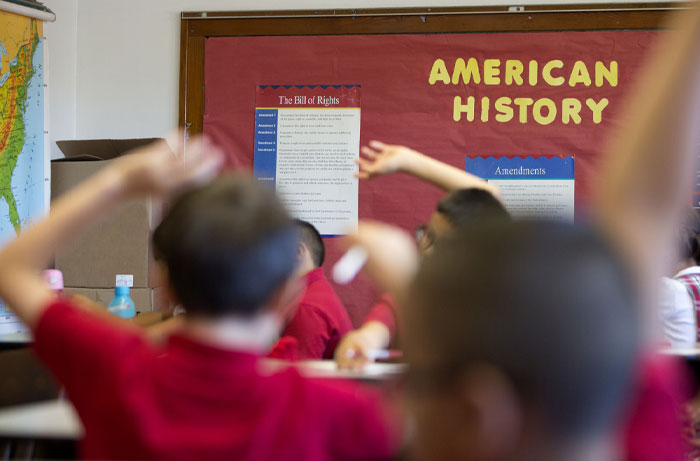 Classroom scene with students raising hands, relating to average IQ in the USA and state academic performance.