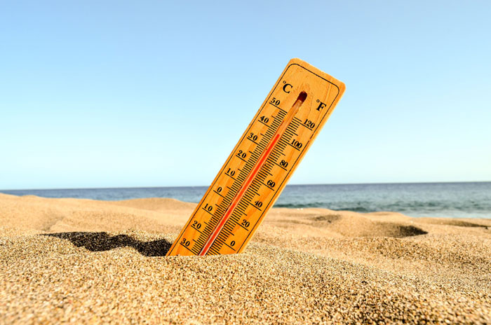 Thermometer showing extreme heat on a sandy beach symbolizing Americans advised to avoid alcohol in 18 states. - 7