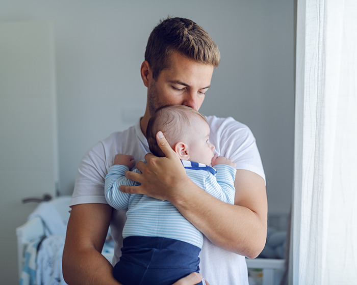Man holding baby girl close with skin-to-skin contact indoors, illustrating baby girl develops micropenis concept. - 12