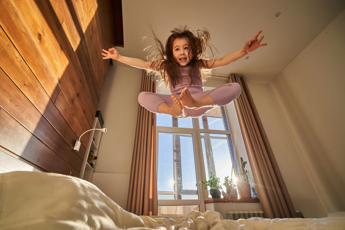 6-year-old girl jumping on bed with energetic excitement during babysitting, showing a sugar rush and mini metalhead vibe. 6-year-old girl jumping on bed with energetic excitement during babysitting, showing a sugar rush and mini metalhead vibe.