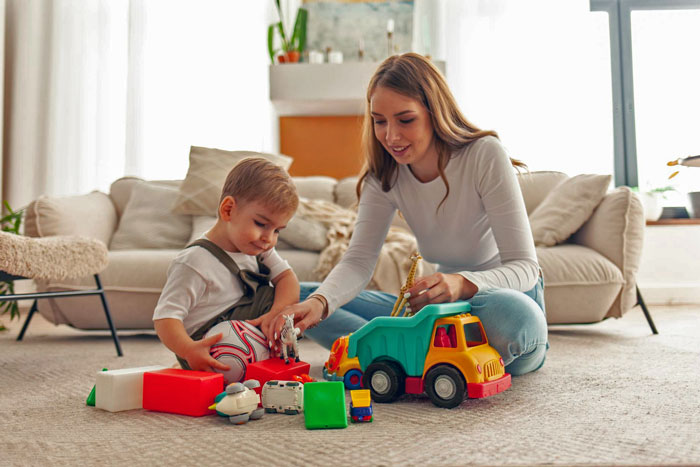 Woman babysitting newphews playing with toys on the floor while a study bible rests nearby in a cozy living room. Woman babysitting newphews playing with toys on the floor while a study bible rests nearby in a cozy living room.