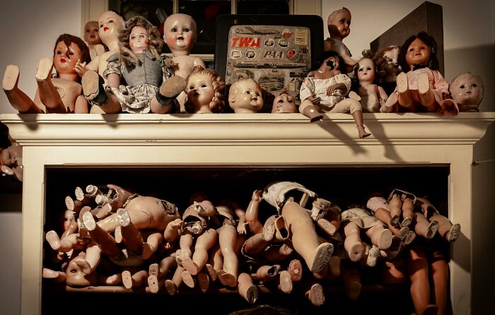 Collection of creepy vintage dolls arranged on shelves, evoking eerie vibes for babysitter creepy stories SEO keyword.