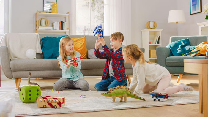 Three children playing with toys on a living room floor, illustrating babysitting siblings and family demands. - 5