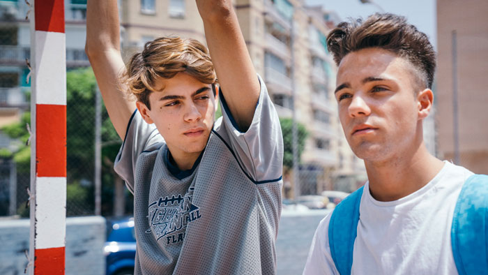 Two young men outdoors in an urban setting, one appearing tired and frustrated, reflecting 22YO sick of babysitting siblings. - 10