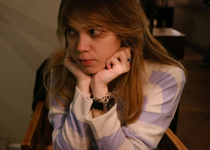 Teen girl sitting alone looking upset as stepmom bans her from family dinners for singing during meals Teen girl sitting alone looking upset as stepmom bans her from family dinners for singing during meals