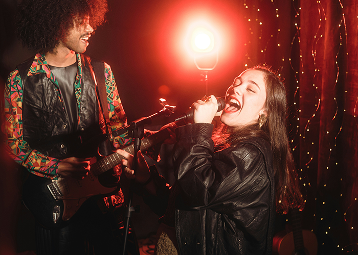 Teen girl singing passionately into a microphone while playing guitar, highlighting stepmom banning teen from family dinners for singing. Teen girl singing passionately into a microphone while playing guitar, highlighting stepmom banning teen from family dinners for singing.