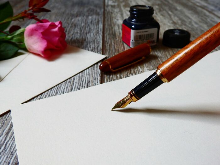 Fountain pen writing on blank paper with ink bottle and rose symbolizing bare minimum or princess treatment choices.