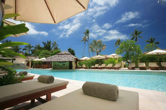 Luxury poolside scene with lounge chairs and umbrellas, offering a princess treatment experience under clear skies.