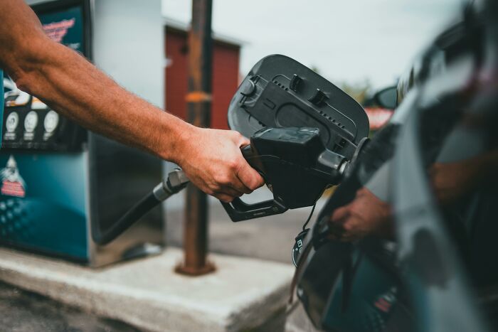 Person refueling a car at a gas station illustrating the concept of bare minimum or princess treatment in service.