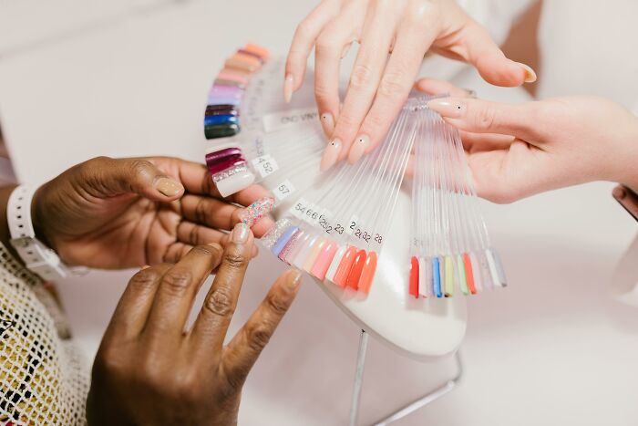Hands choosing nail polish colors from a palette, illustrating the contrast between bare minimum and princess treatment.