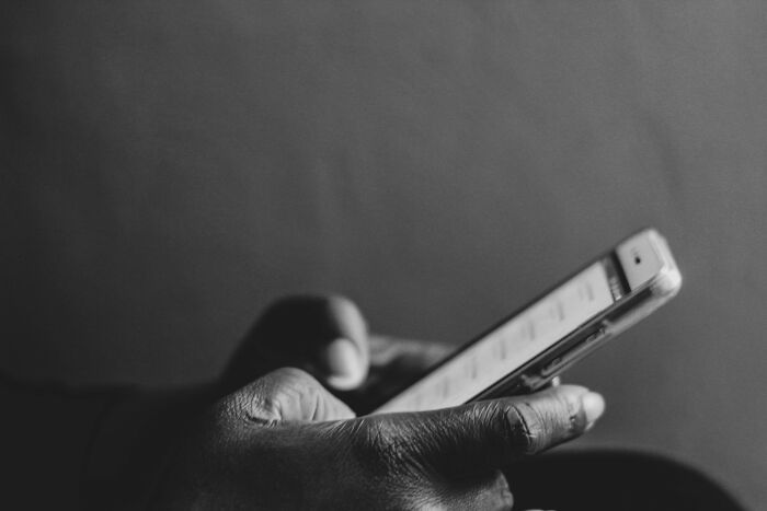 Close-up of a hand holding a smartphone, highlighting the contrast between bare minimum and princess treatment concepts.