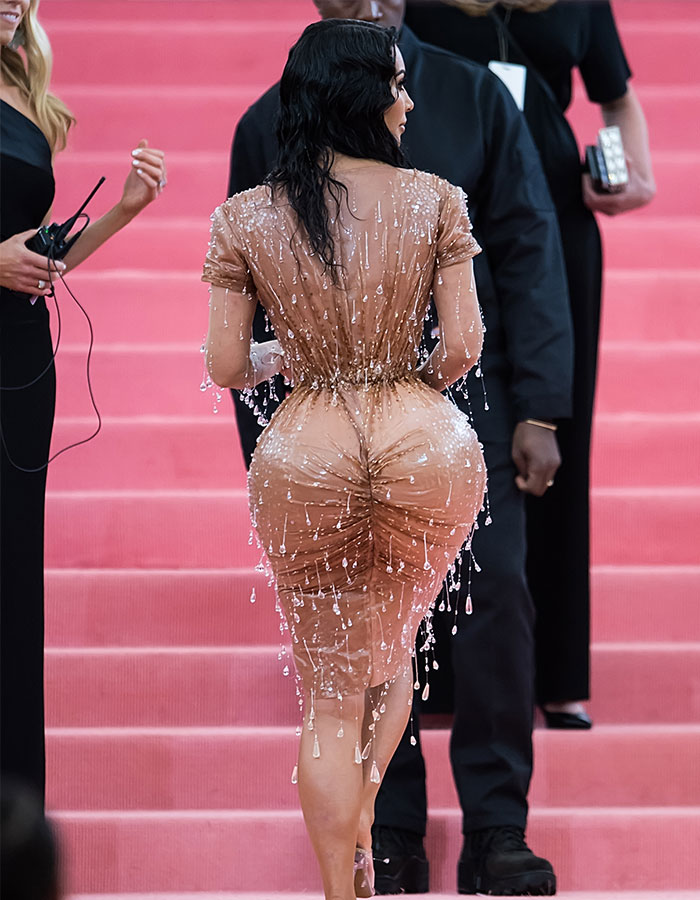 Woman in a wet, body-hugging dress highlighting BBL curves, with focus on BBL smell concerns discussed by doctors.