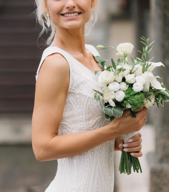 Bride in a detailed white dress holding a bouquet of white flowers, symbolizing family lore and special moments.