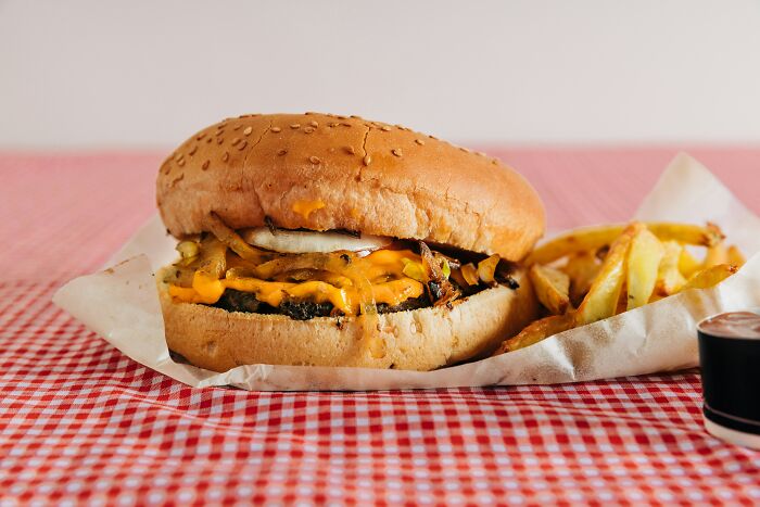 Close-up of a cheeseburger and fries on a red checkered tablecloth, related to McDonald's employees' bizarre experiences.