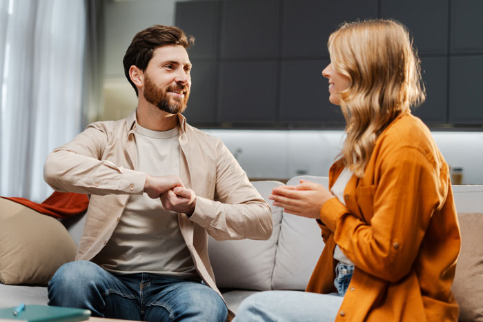 Couple having a tense conversation on couch with lady shocked and husband possibly hiding an affair in a modern living room.
