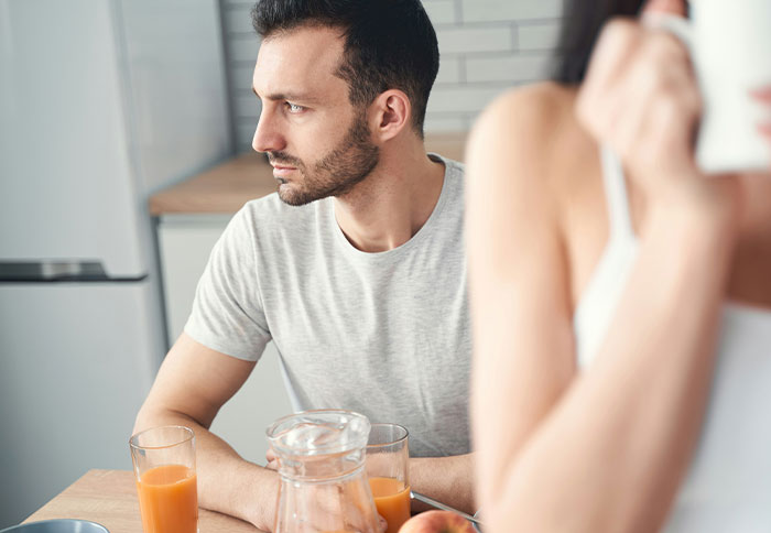 Man looking concerned while woman checks email nearby, illustrating best friend saw girlfriend with another man situation.