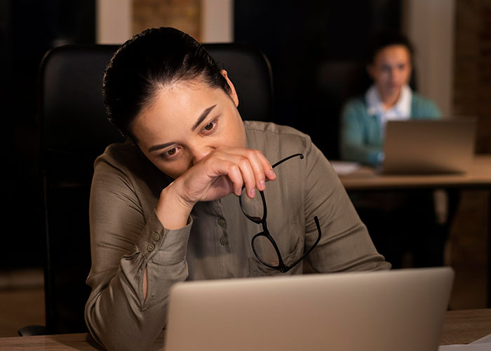 Woman looking stressed while holding glasses and staring at a laptop screen, illustrating life cheat codes concept. - 28