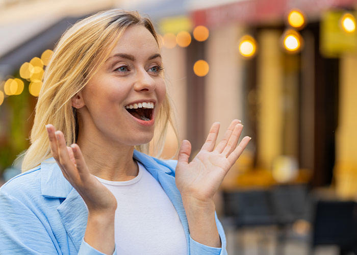 Young woman excitedly gestures with hands outdoors, illustrating life cheat codes for easier living and better success. - 43