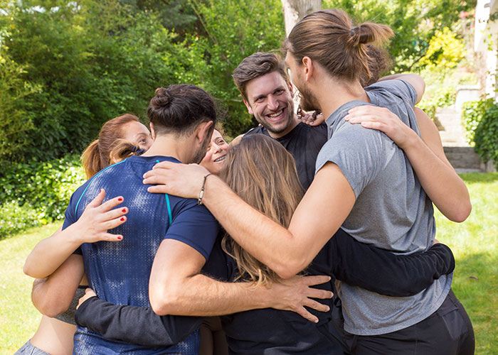 Group of friends smiling and hugging outdoors, illustrating the joy of life cheat codes for better relationships. - 32