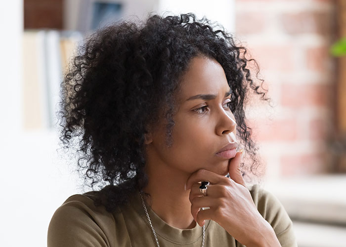 Young woman thinking deeply indoors, illustrating the concept of life cheat codes for better living and personal growth. - 35