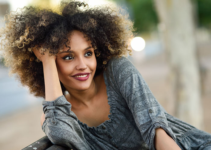 Young woman outdoors smiling and relaxing, representing a carefree lifestyle and useful life cheat codes. - 33