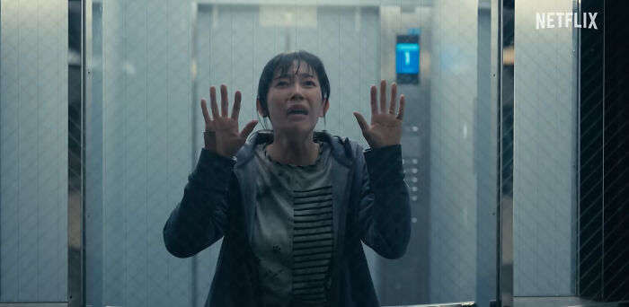 Woman with hands pressed on glass, anxious and trapped, in a scene from one of the best Netflix shows trending among netizens. - 9