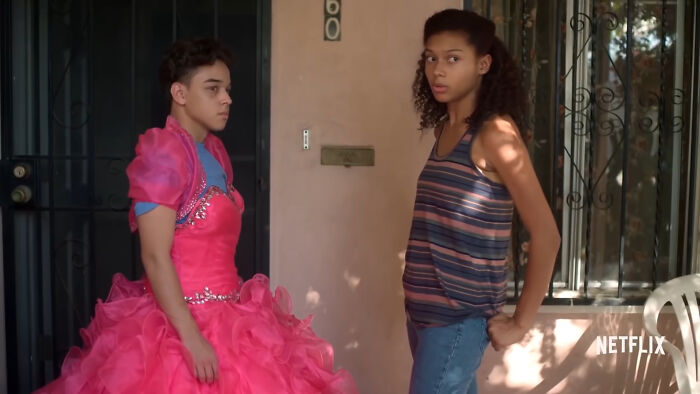 Two young people standing outside a house, one wearing a bright pink dress, from popular Netflix shows. - 22