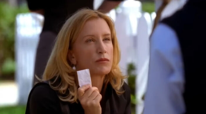 Woman with blonde hair holding a small white packet, watching intently in a scene from popular Netflix shows. - 31