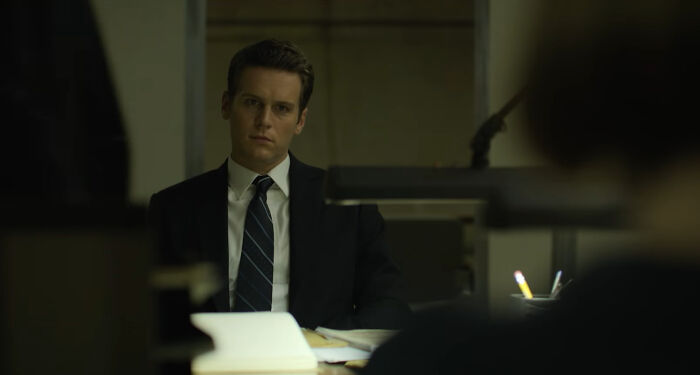 Man in a suit and tie sitting in an office, scene from one of the best Netflix shows that keep viewers coming back - 1