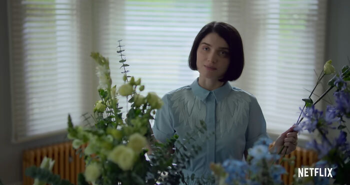 Young woman arranging flowers indoors, representing best Netflix shows that keep viewers coming back for more. - 12