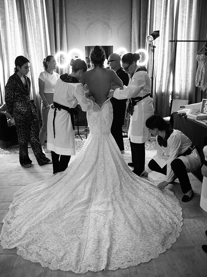 Lauren Sanchez in a wedding gown being adjusted by stylists amid discussions of photoshopped wedding pictures and editing blunders.