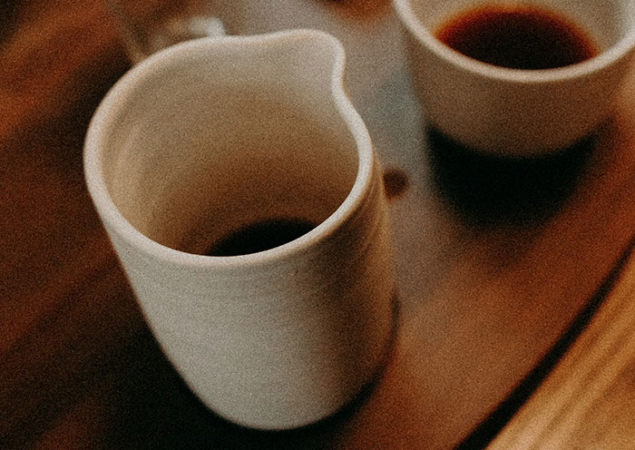Ceramic cups of dark coffee on a wooden table hinting at home red flags during a first date setting.