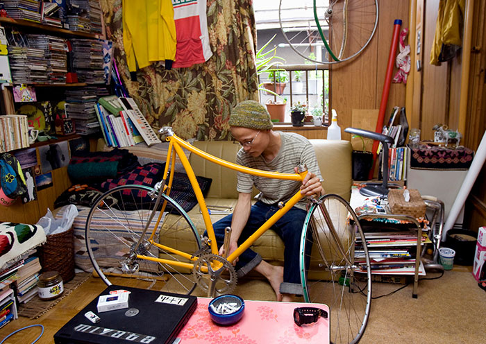 Person fixing a yellow bike in a cluttered room showing home red flags that turn a first date into a last one.