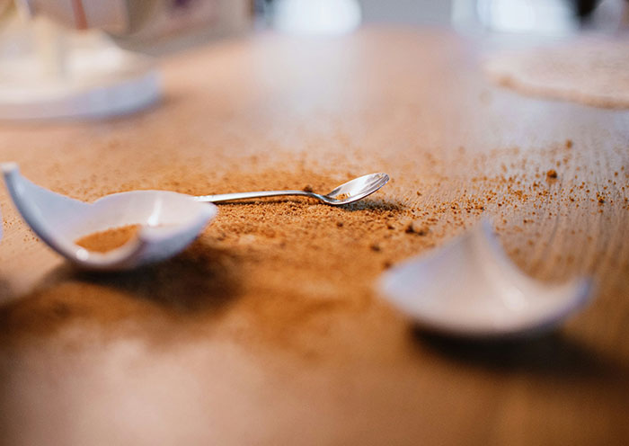 Broken white bowl and spilled powder on wooden surface, illustrating home red flags during a first date.