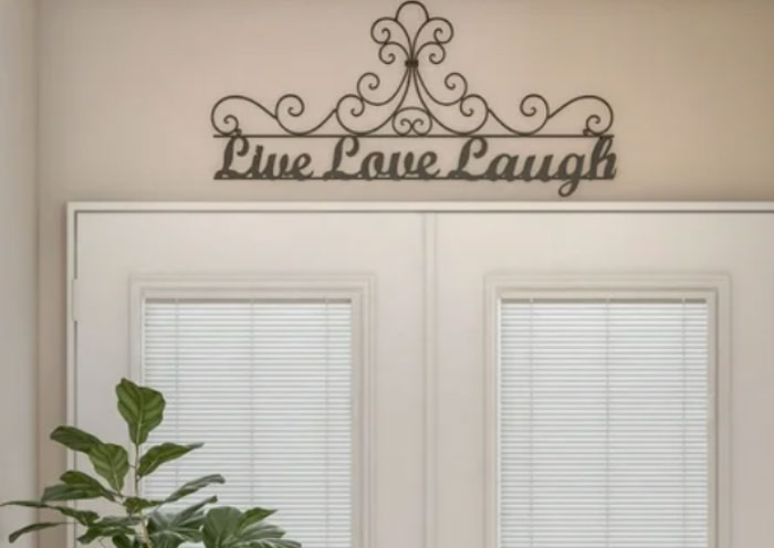 Decorative Live Love Laugh sign above a home door with blinds and indoor plants, highlighting home red flags concept.