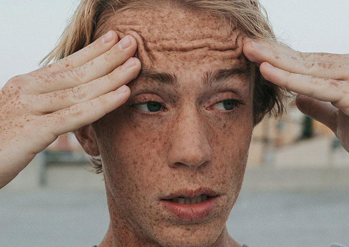 Young man with freckles showing stress and discomfort, illustrating home red flags that turn a first date into a last one.