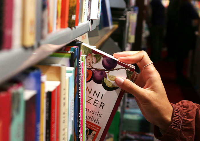 Person selecting a book from a shelf, illustrating home red flags that can turn a first date into a last one.