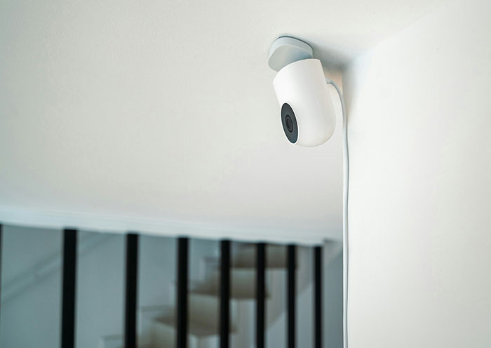 White home security camera mounted on ceiling corner monitoring stairs, highlighting common home red flags during first dates.