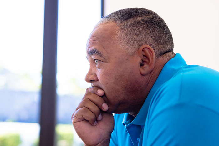 Man in a blue shirt deep in thought, representing a man buying wife’s childhood home amid family demands. - 1