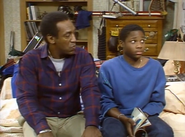 Bill Cosby and Malcolm-Jamal Warner sitting together in a living room scene from The Cosby Show. - 3