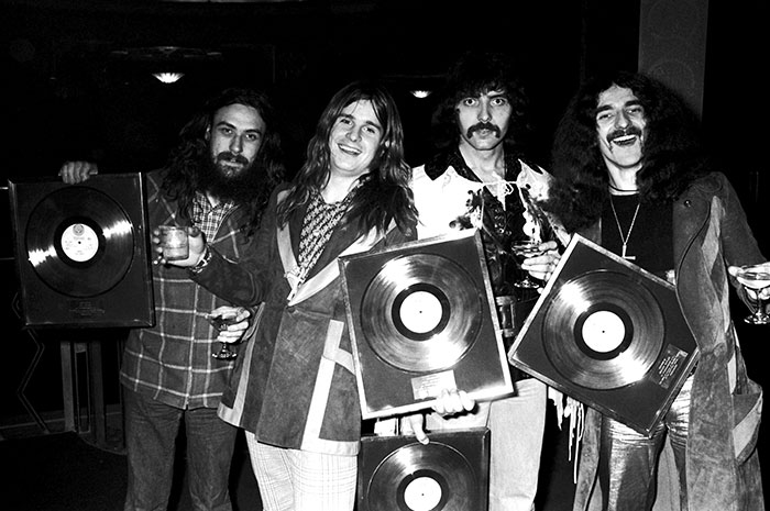 Black Sabbath members holding gold records, reflecting on their emotional statements after Ozzy's passing.