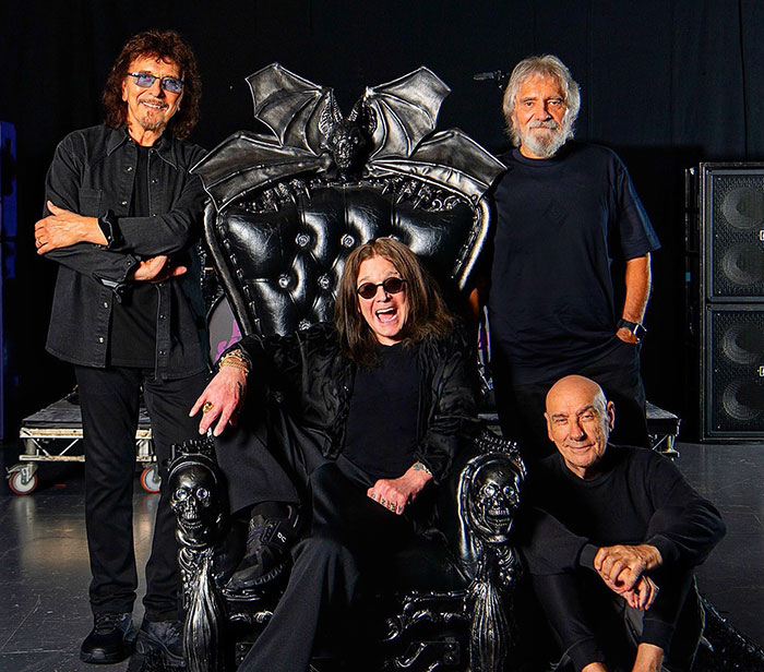 Black Sabbath members posing around a gothic throne, reflecting on Ozzy's passing with emotional statements.