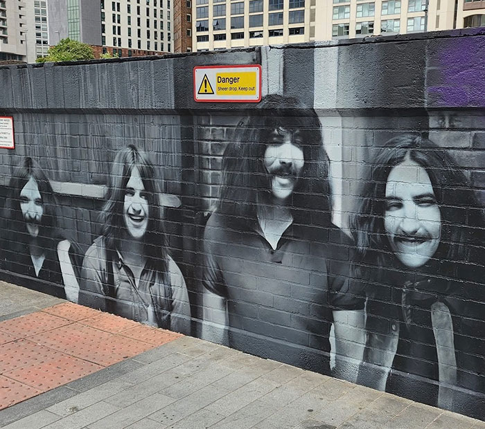 Black Sabbath mural painted on brick wall in urban area, reflecting tribute and emotional statements on Ozzy's passing.