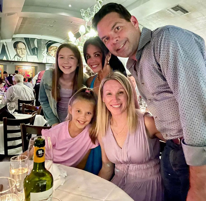 Family smiling together at a restaurant, representing sisters who lost their lives in Texas floods found holding hands.