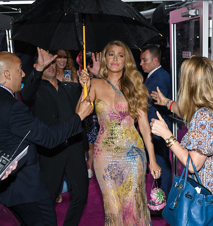 Blake Lively attending event in glamorous dress as security holds umbrella on a rainy night. - 4