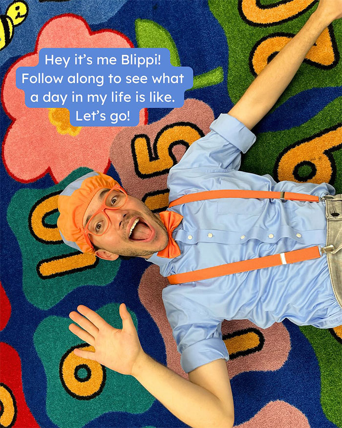 Blippi lying on colorful carpet with orange hat and suspenders, engaging kids’ content audience in fun and energetic pose. - 2