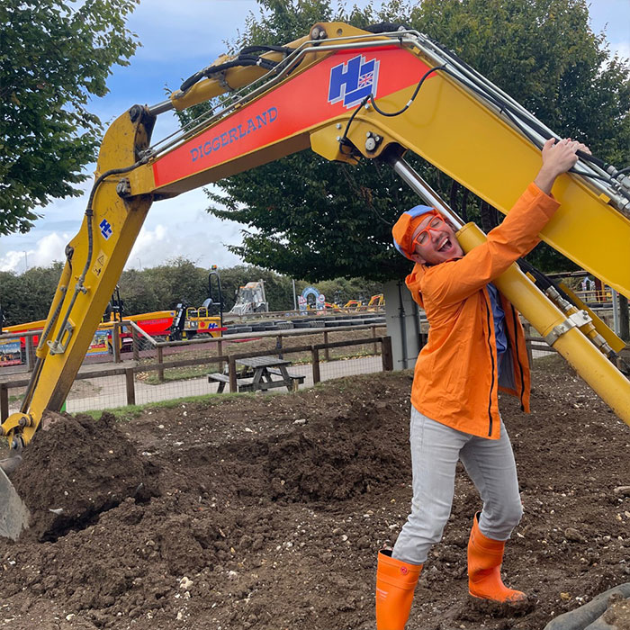 Blippi in orange outfit and boots playing with a yellow digger, highlighting Blippi net worth and kids content gold rush trends. - 7