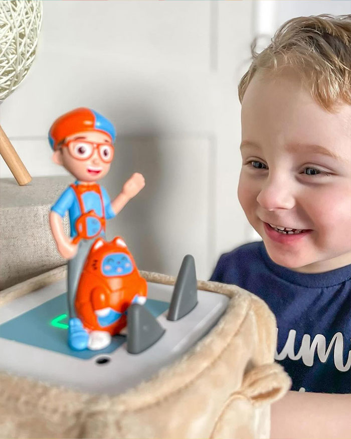 Young child smiling and playing with Blippi toy figure, illustrating Blippi net worth and kids content growth in 2025. - 9