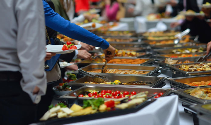 People serving food from a buffet, illustrating a guy nagging his girlfriend to eat more and causing a breakup.